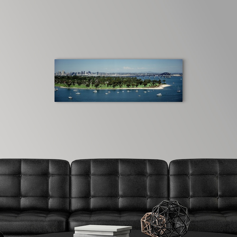 A modern room featuring Panoramic photograph of many small boats and an area of land with many trees near the bay, next t...