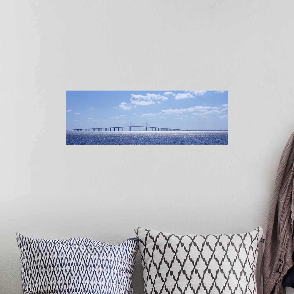 A bohemian room featuring Panoramic photograph of overpass crossing an ocean on a cloudy day.
