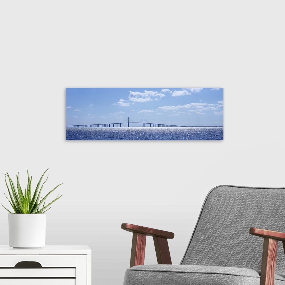 A modern room featuring Panoramic photograph of overpass crossing an ocean on a cloudy day.