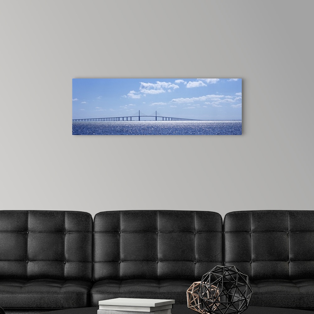 A modern room featuring Panoramic photograph of overpass crossing an ocean on a cloudy day.
