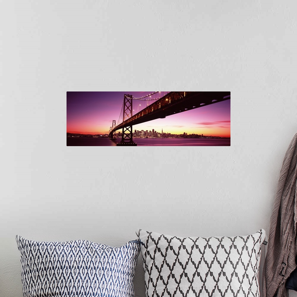 A bohemian room featuring Large panoramic photo print of a long bridge leading to a lit up city off in the distance at sunset.