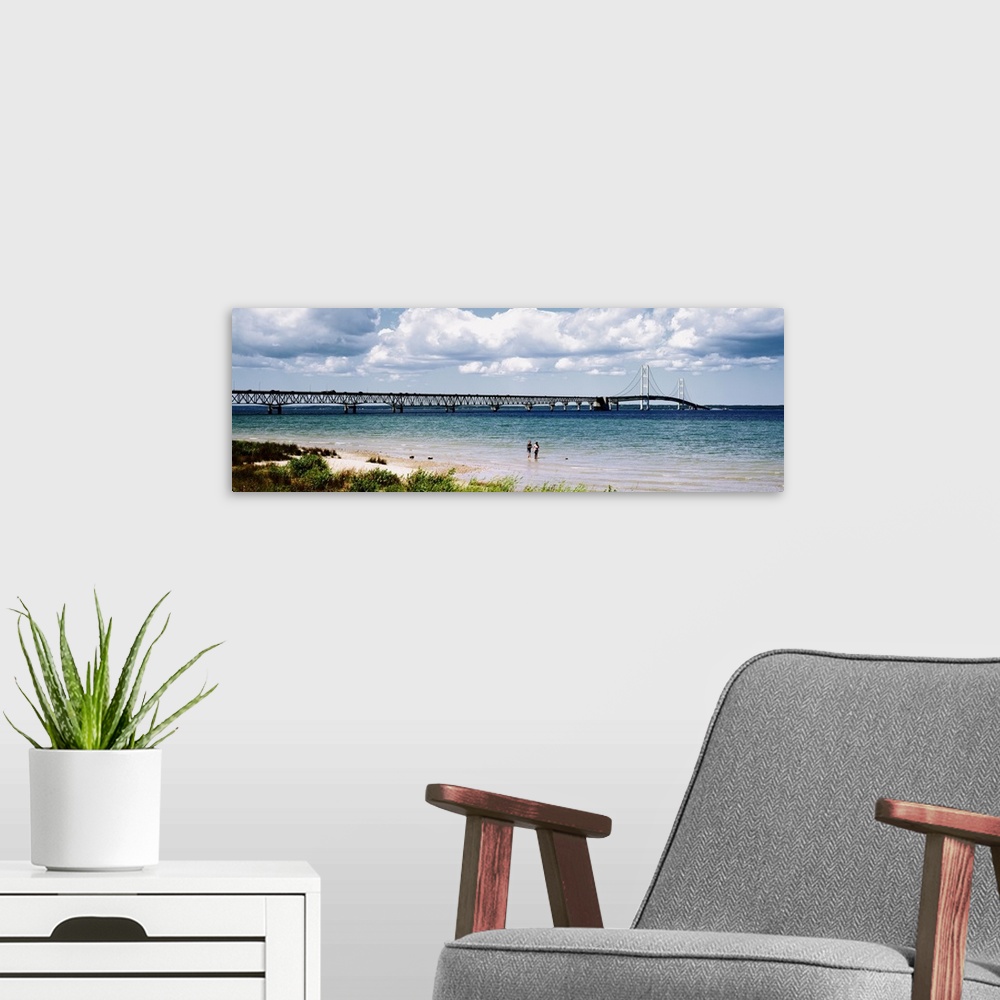 A modern room featuring Panoramic picture of a massive bridge that stretches across a lake in Michigan. Some beach on the...