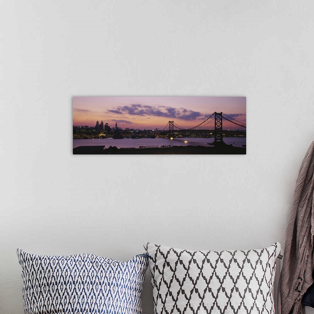 A bohemian room featuring Panoramic photograph of city skyline and overpass at dusk.  The sun is setting, the sky is cloudy...