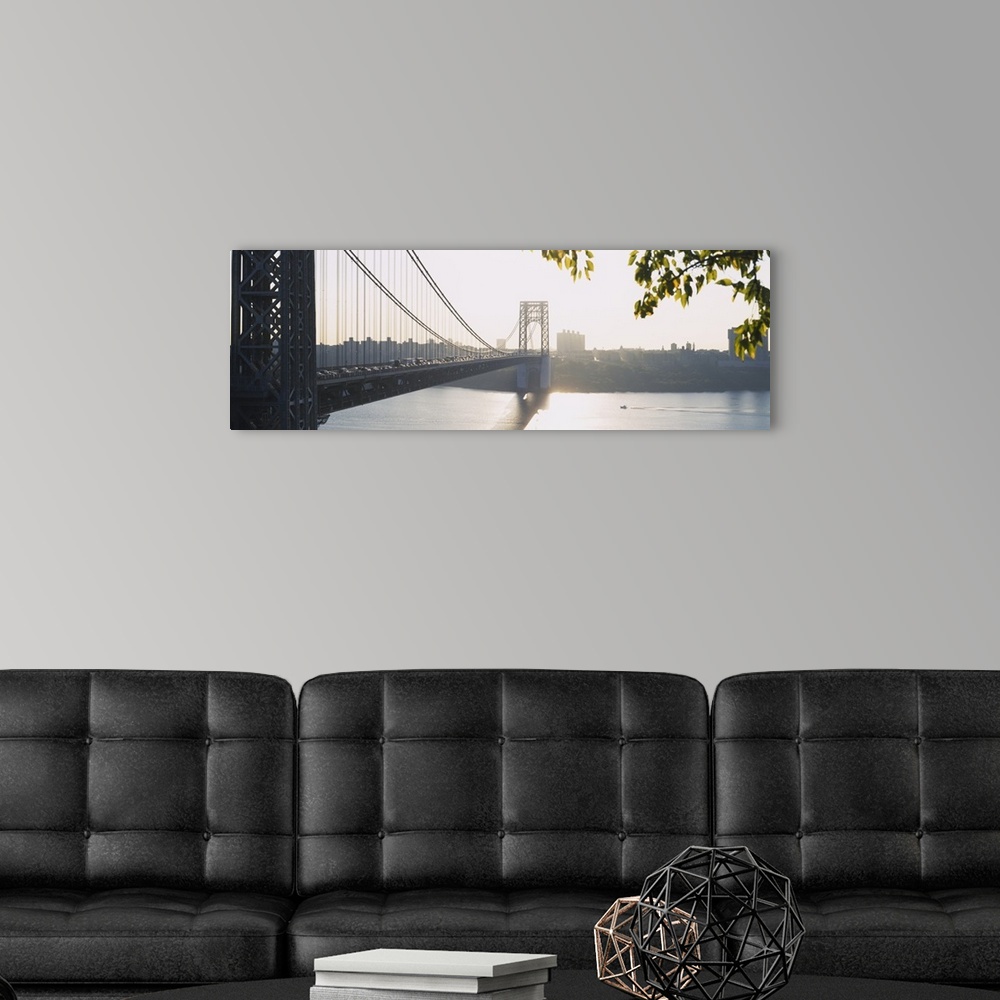 A modern room featuring The sun sets off in the distance over the George Washington bridge which is photographed in wide ...