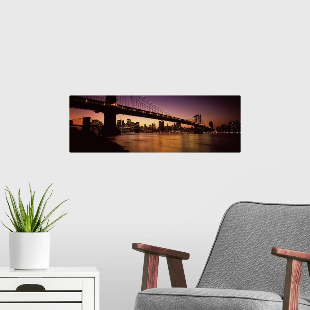 A modern room featuring Panoramic photograph of overpass crossing body of water, connecting two cities at sunset.  The ci...