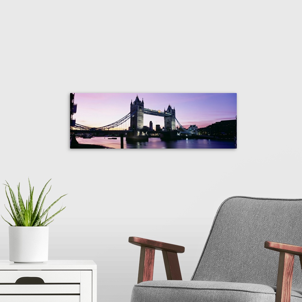 A modern room featuring Panorama of the Tower Bridge at dusk with color reflections in the Thames River of London, England.