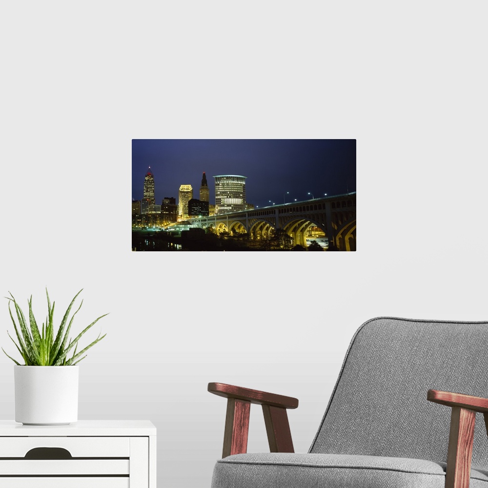 A modern room featuring Panoramic photograph of overpass leading to a lit up collage of buildings at dusk.