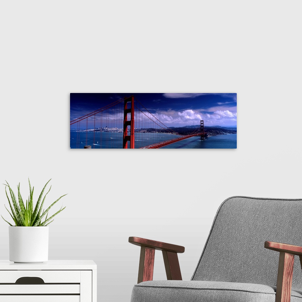A modern room featuring Panoramic photograph of the suspension bridge over the mouth of the bay on a sunny day as clouds ...