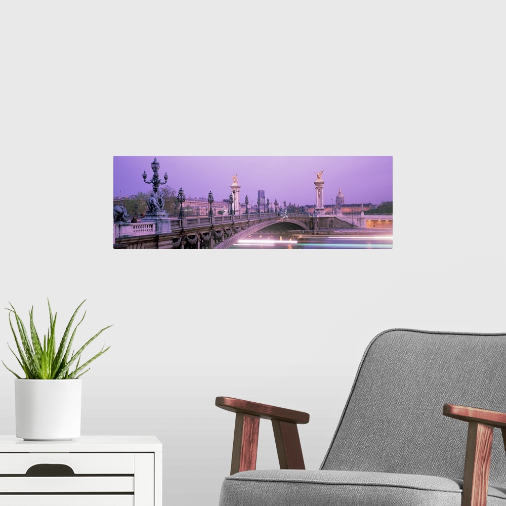 A modern room featuring This panoramic photograph is a time lapsed photo that captures streaks of lights of boats passing...