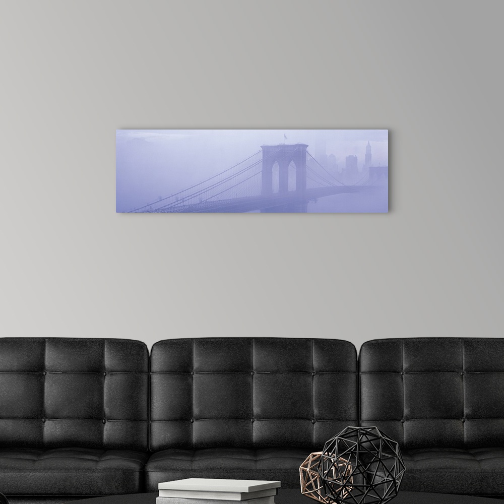 A modern room featuring Panoramic photograph on a giant wall hanging of fog surrounding New York's famous Brooklyn Bridge...