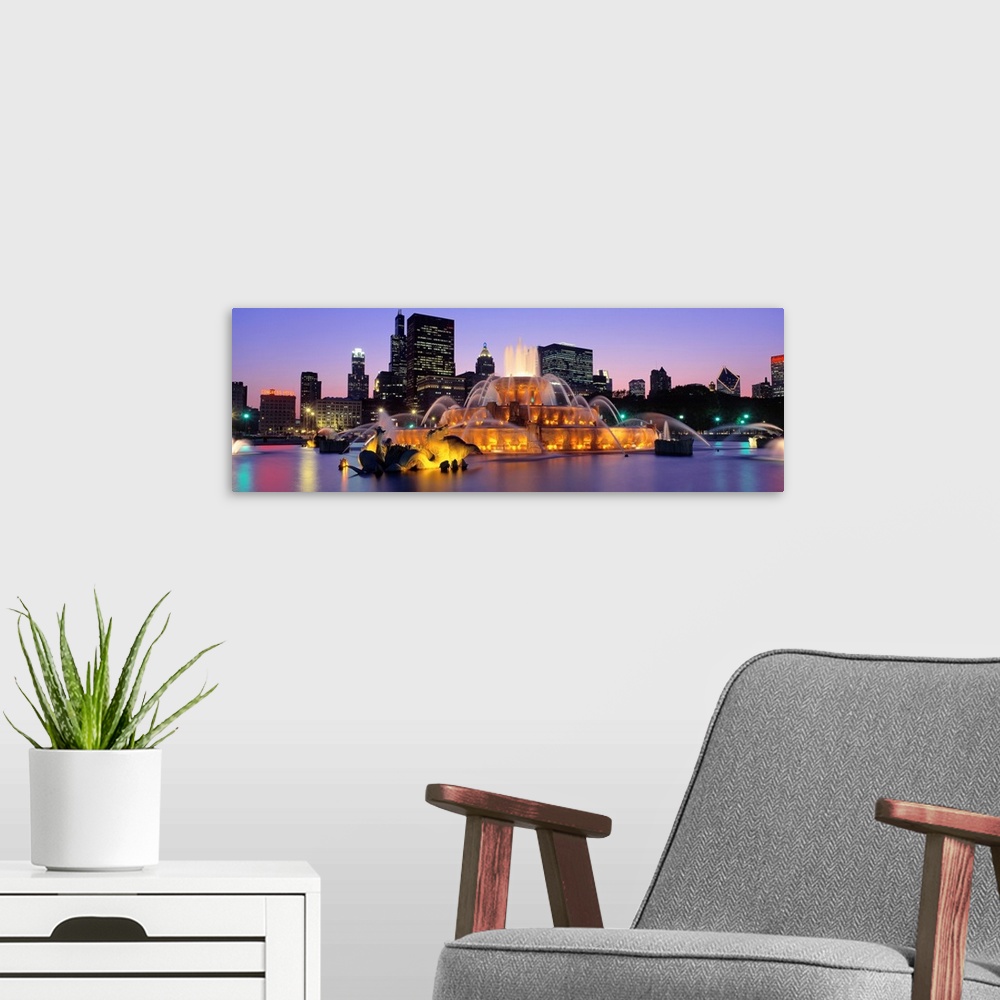 A modern room featuring Buckingham Fountain in Chicago lit up at night.
