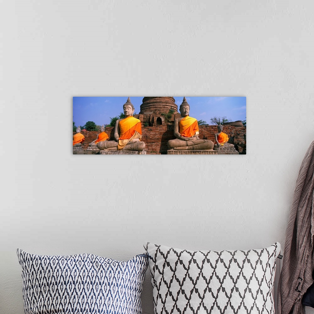 A bohemian room featuring Big horizontal photograph of many sitting Buddha statues, cloaked in golden orange fabric, a larg...