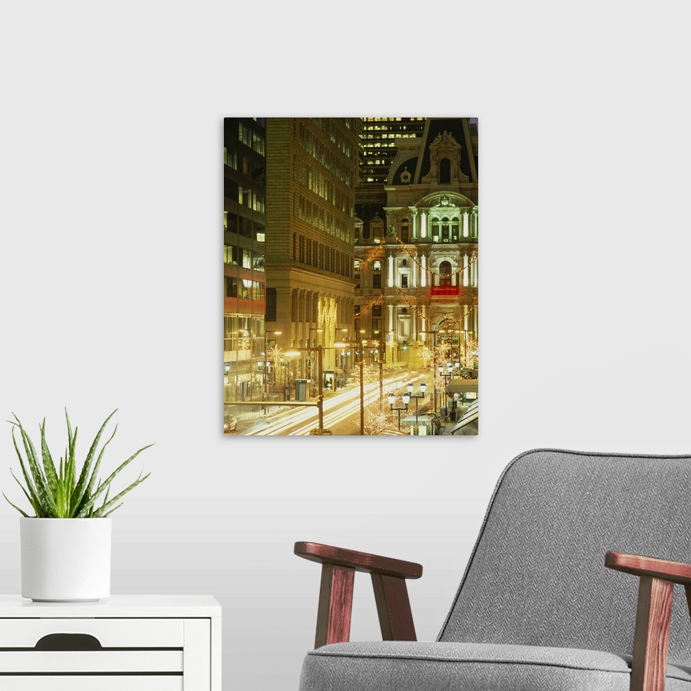 A modern room featuring Vertical photograph on a big canvas of a brightly lit street in Philadelphia and city hall lit at...