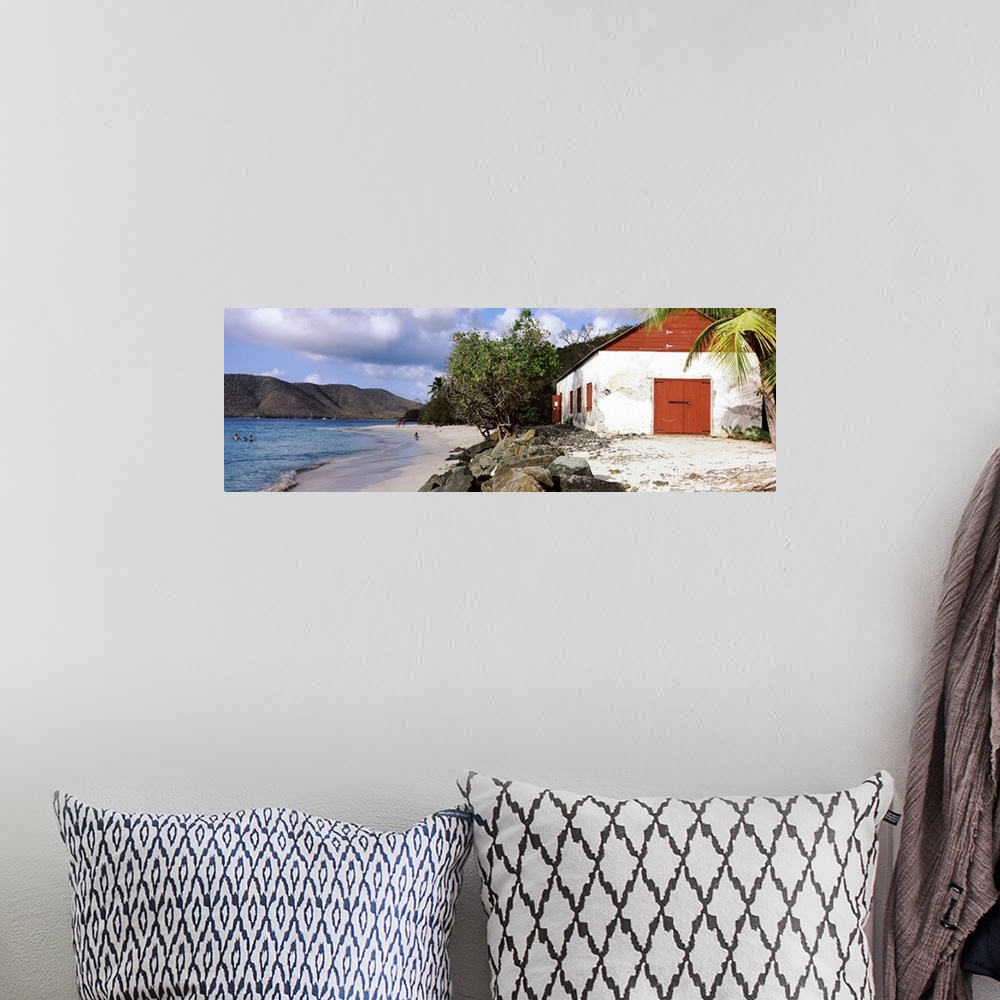 A bohemian room featuring Wide angle photograph taken of a building sitting on a beach with rocks sitting just in front of ...