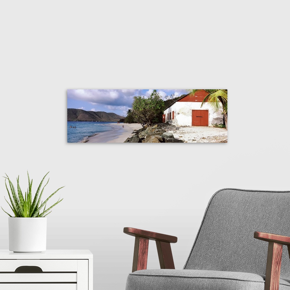 A modern room featuring Wide angle photograph taken of a building sitting on a beach with rocks sitting just in front of ...