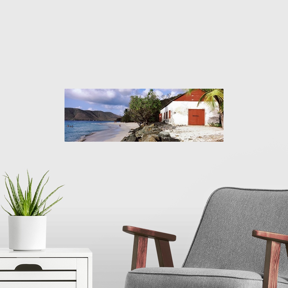A modern room featuring Wide angle photograph taken of a building sitting on a beach with rocks sitting just in front of ...