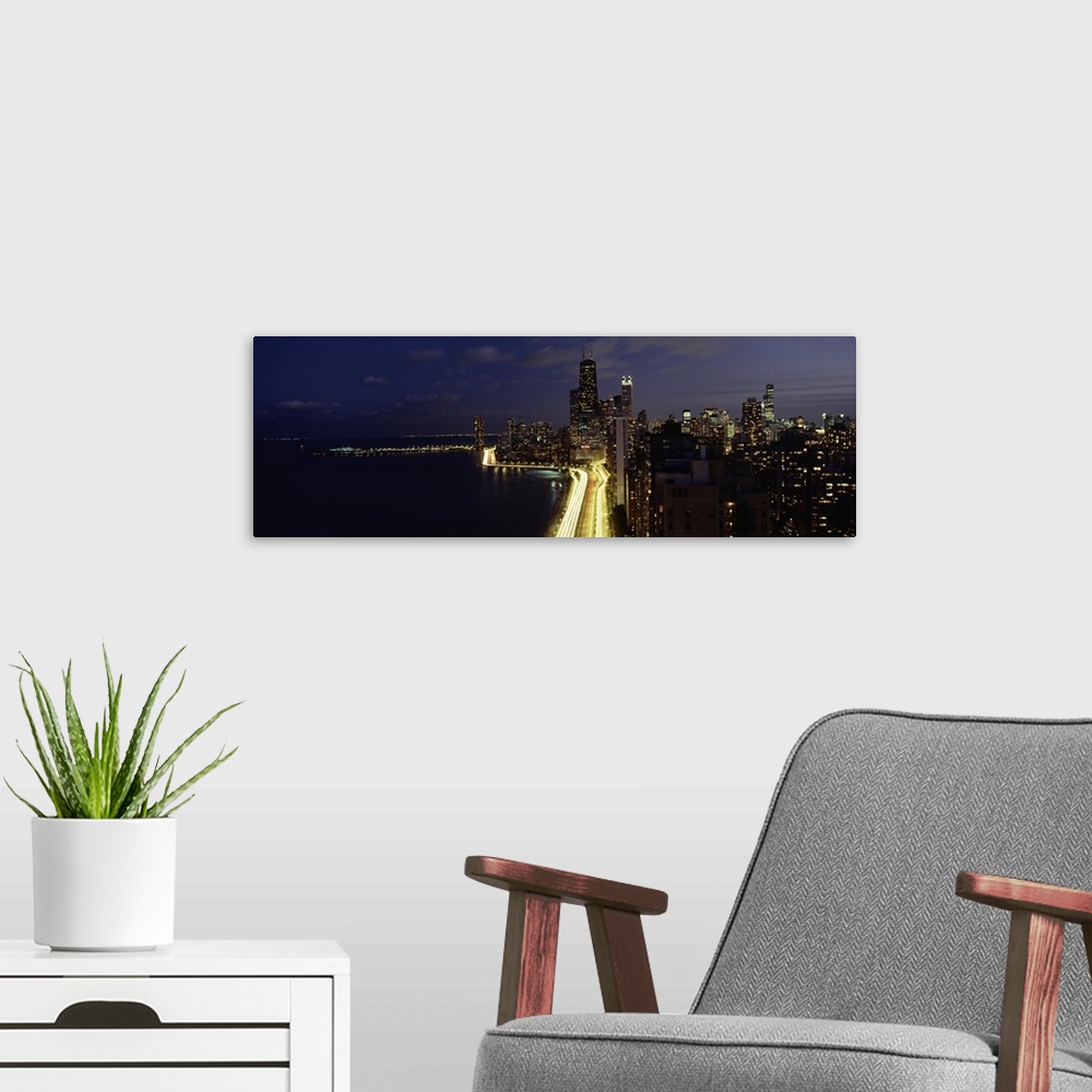 A modern room featuring Buildings along a lake lit up at night, Lakeshore Drive, Navy Pier, Lake Michigan, Chicago, Cook ...