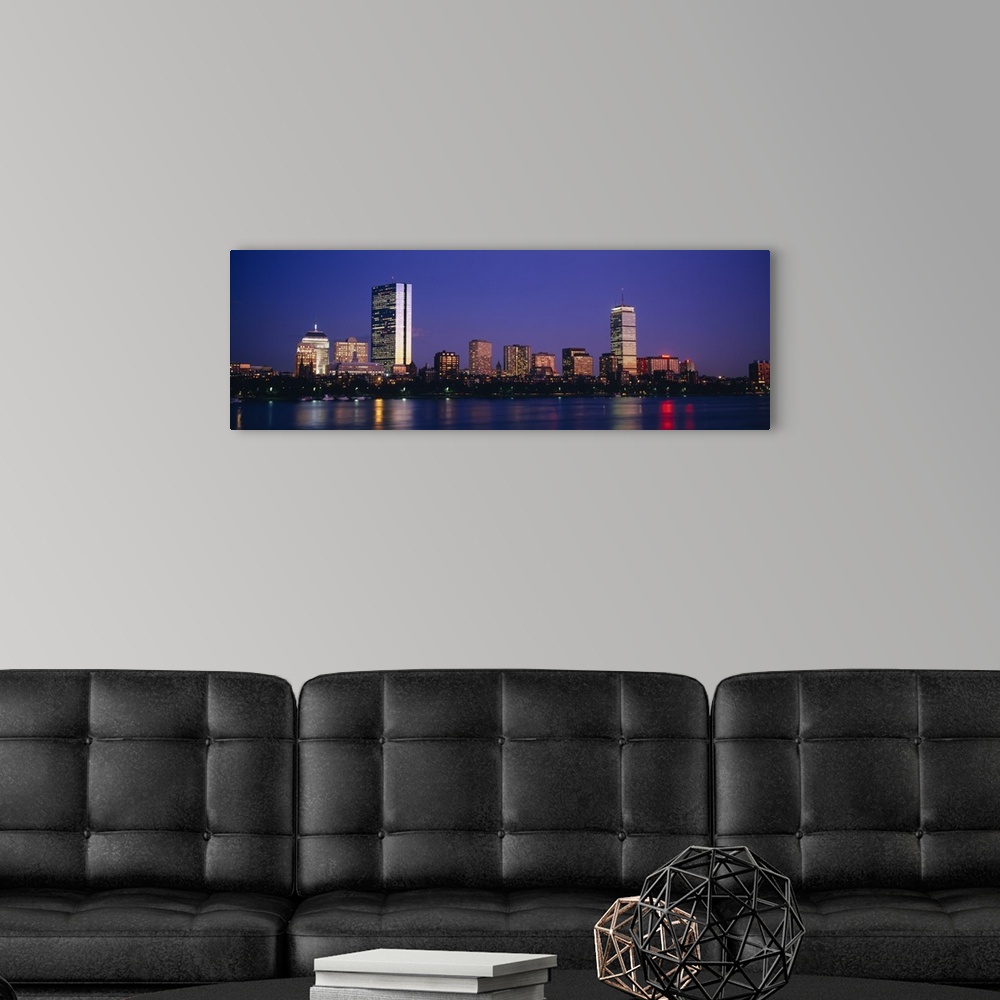 A modern room featuring Large panoramic photograph of skyscrapers and other buildings lit up lining the Charles River in ...