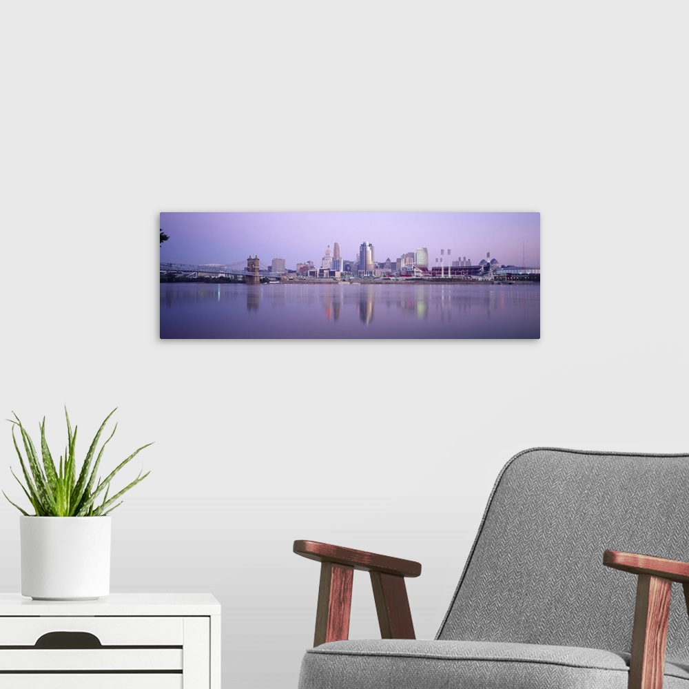 A modern room featuring A wide angle photograph is taken from across the river of the skyline in Cincinnati during the ev...