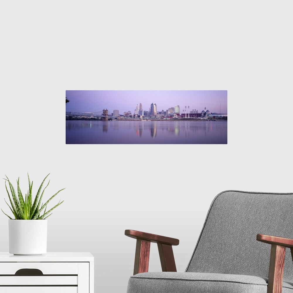 A modern room featuring A wide angle photograph is taken from across the river of the skyline in Cincinnati during the ev...