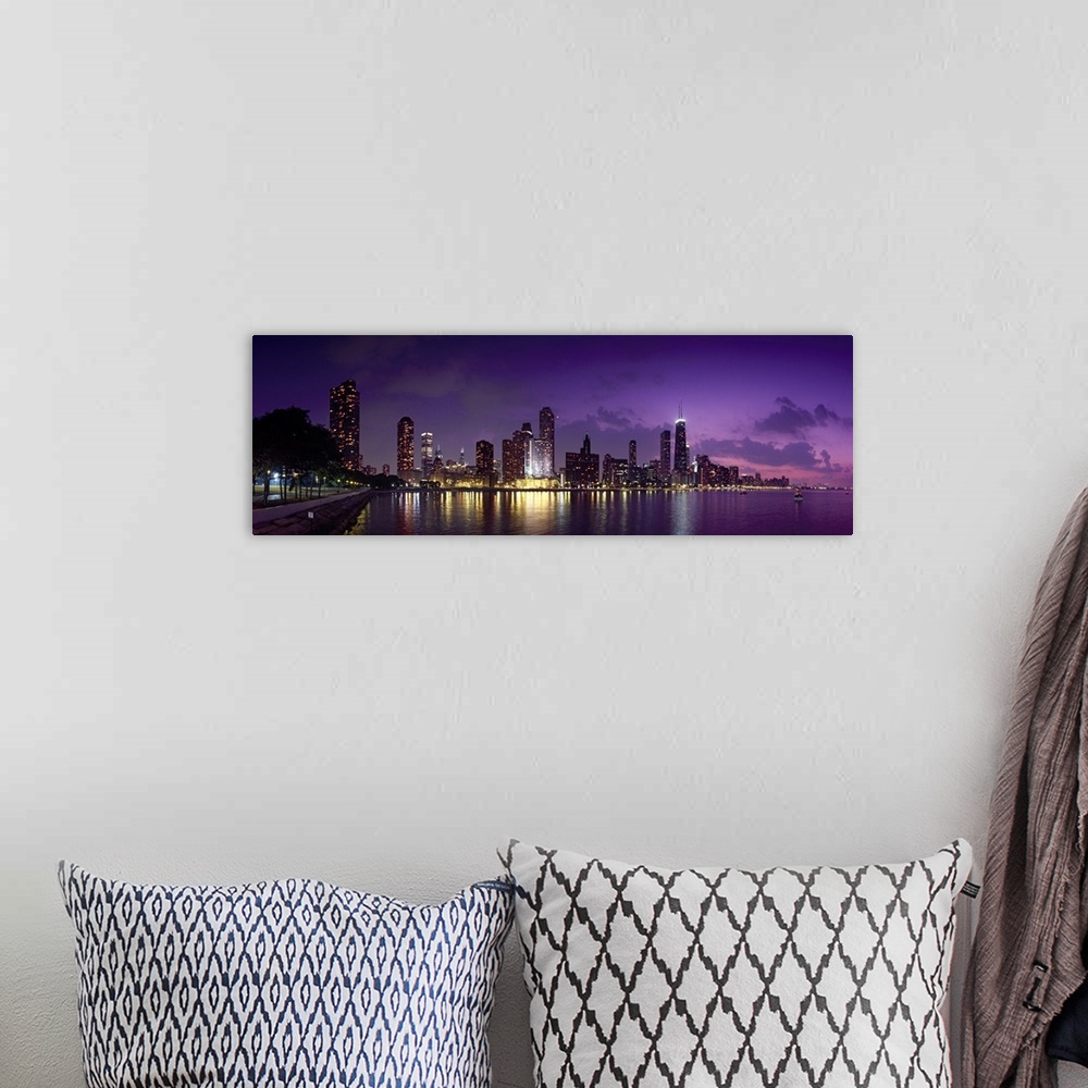 A bohemian room featuring Long canvas photo of a lit up cityscape at sunset by a waterfront.