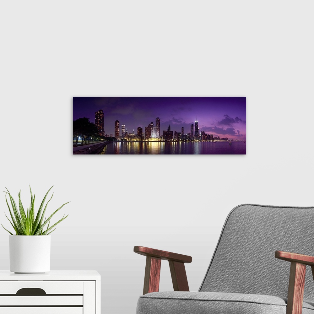 A modern room featuring Long canvas photo of a lit up cityscape at sunset by a waterfront.
