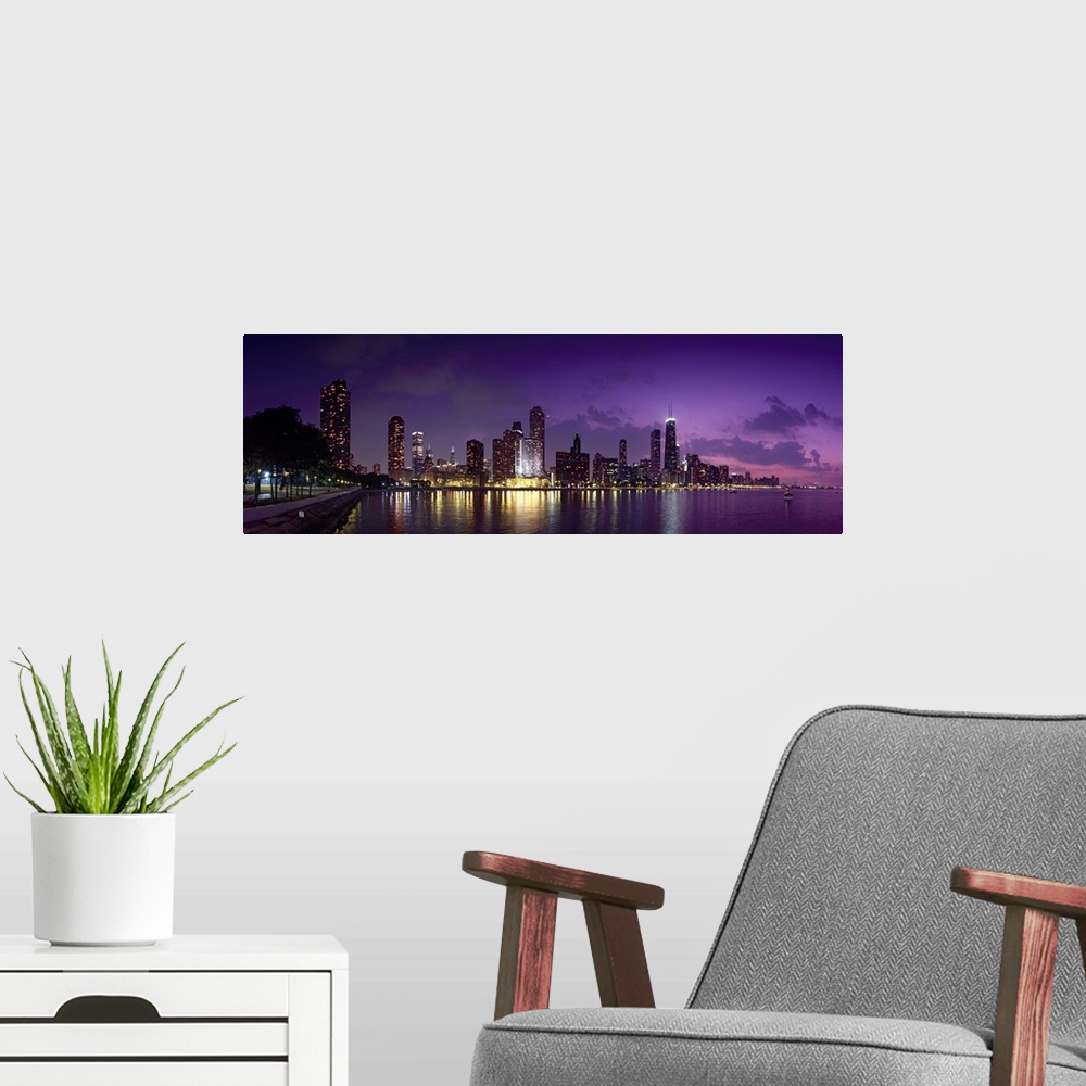 A modern room featuring Long canvas photo of a lit up cityscape at sunset by a waterfront.