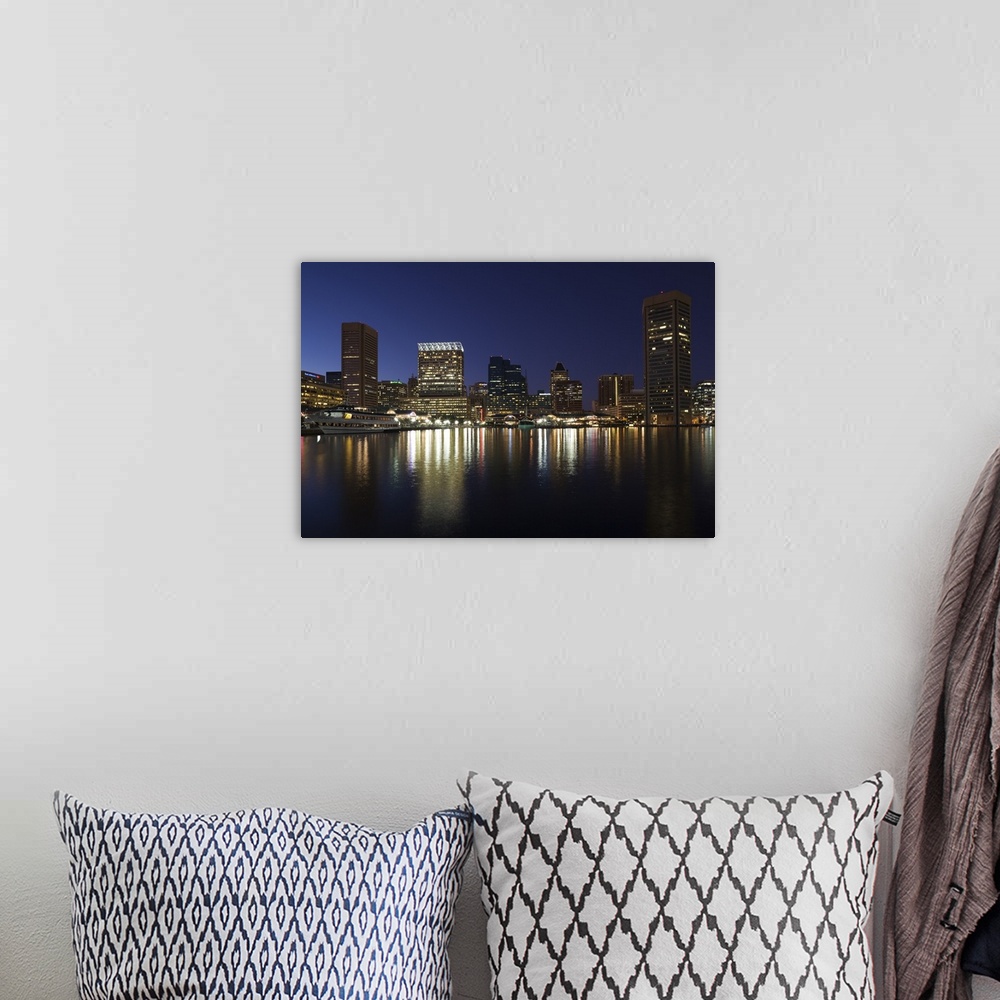 A bohemian room featuring City skyscrapers reflecting their lights onto the water of the Inner Harbor in Baltimore, Maryland.