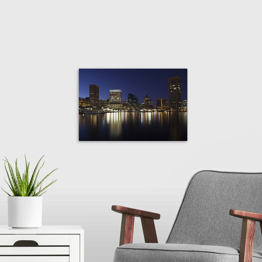 A modern room featuring City skyscrapers reflecting their lights onto the water of the Inner Harbor in Baltimore, Maryland.