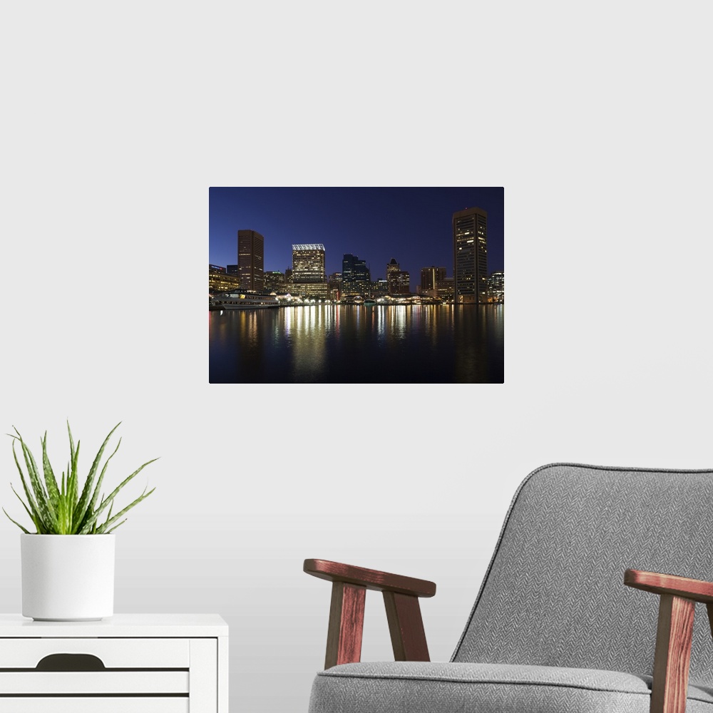 A modern room featuring City skyscrapers reflecting their lights onto the water of the Inner Harbor in Baltimore, Maryland.