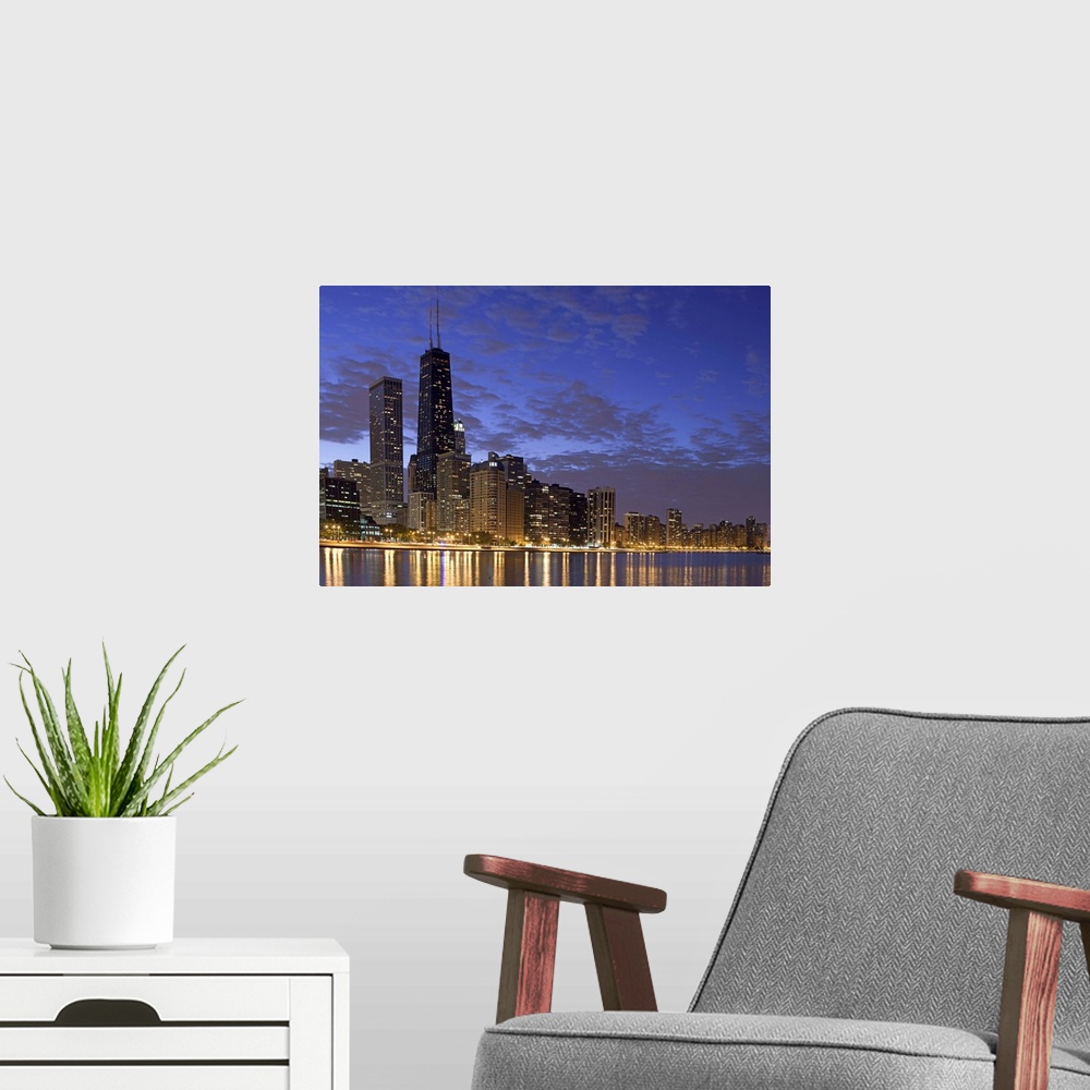A modern room featuring Large photo on canvas of the Chicago cityscape lit up at night reflecting into the nearby waterfr...