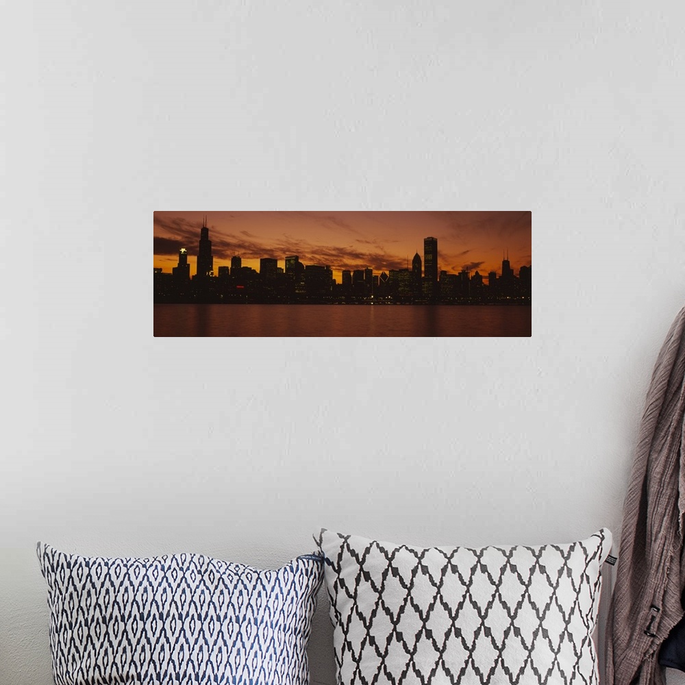 A bohemian room featuring Lake Michigan reflects the setting sun as lakeside buildings light up the night in downtown Chica...