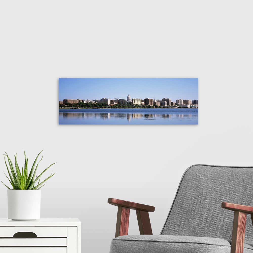 A modern room featuring Panoramic picture taken of the city skyline in the capitol of Wisconsin. There is a body of water...