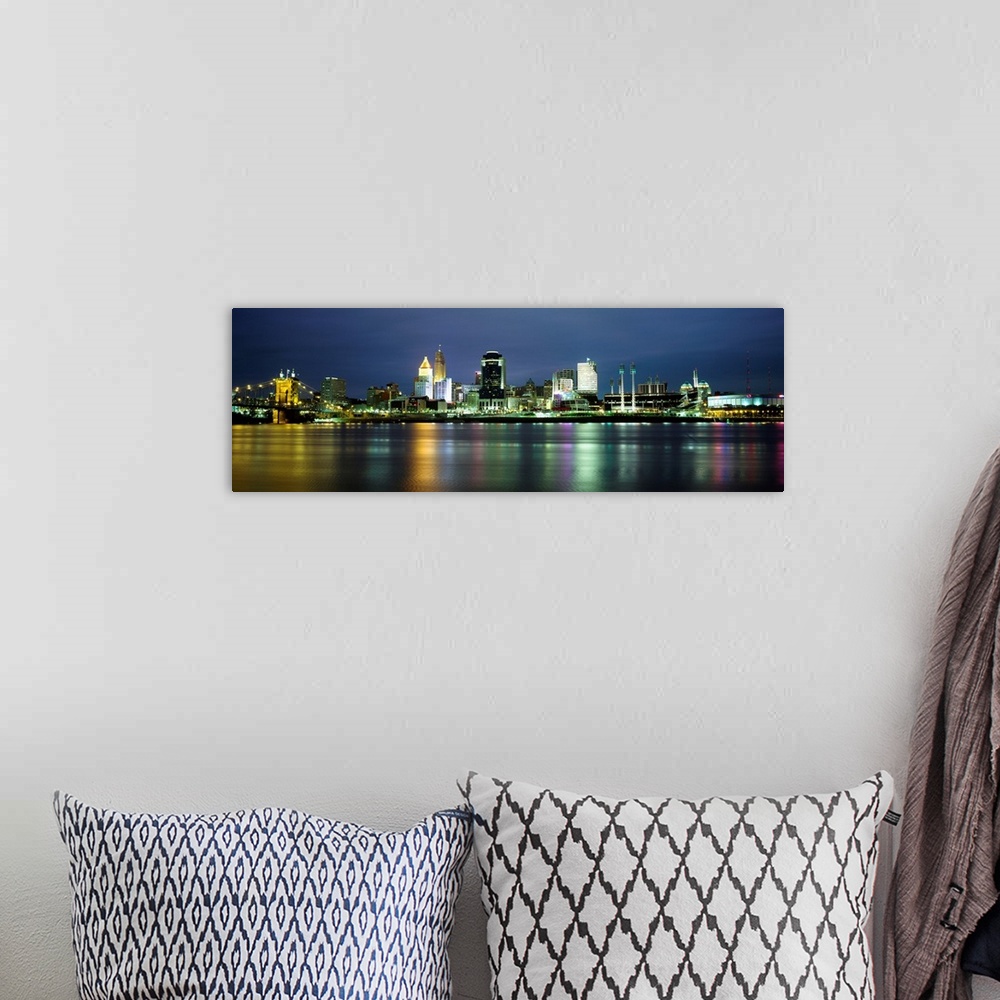 A bohemian room featuring A panoramic cityscape of downtown city lights reflecting in the water and photographed at night.