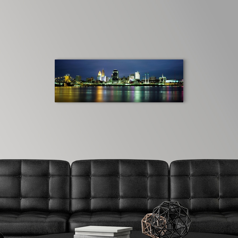 A modern room featuring A panoramic cityscape of downtown city lights reflecting in the water and photographed at night.