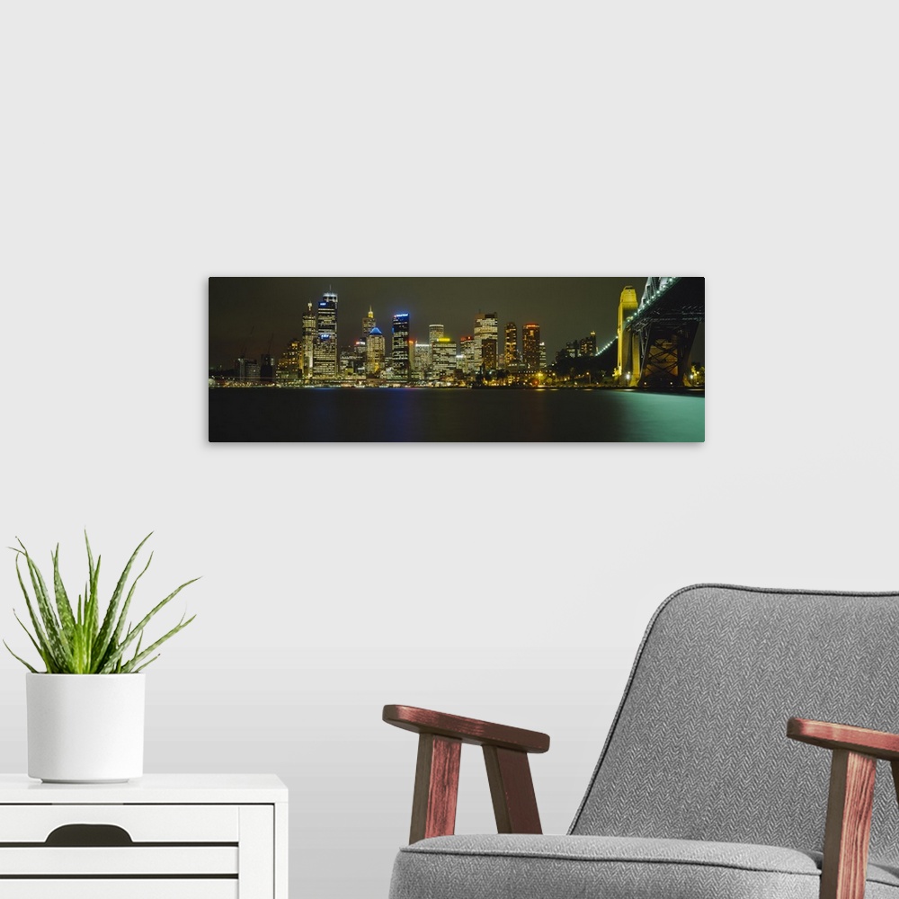 A modern room featuring Buildings at the waterfront lit up at night, Sydney Harbor Bridge, Sydney, New South Wales, Austr...