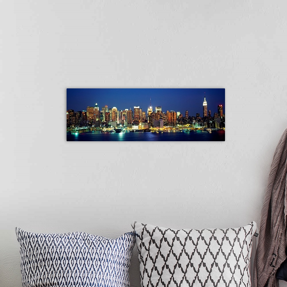 A bohemian room featuring A panoramic photograph of the Manhattan shore and skyscrapers illuminated at night.