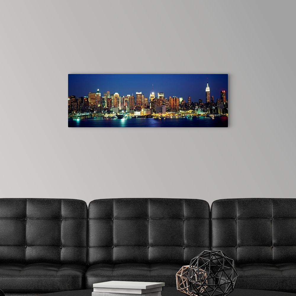 A modern room featuring A panoramic photograph of the Manhattan shore and skyscrapers illuminated at night.