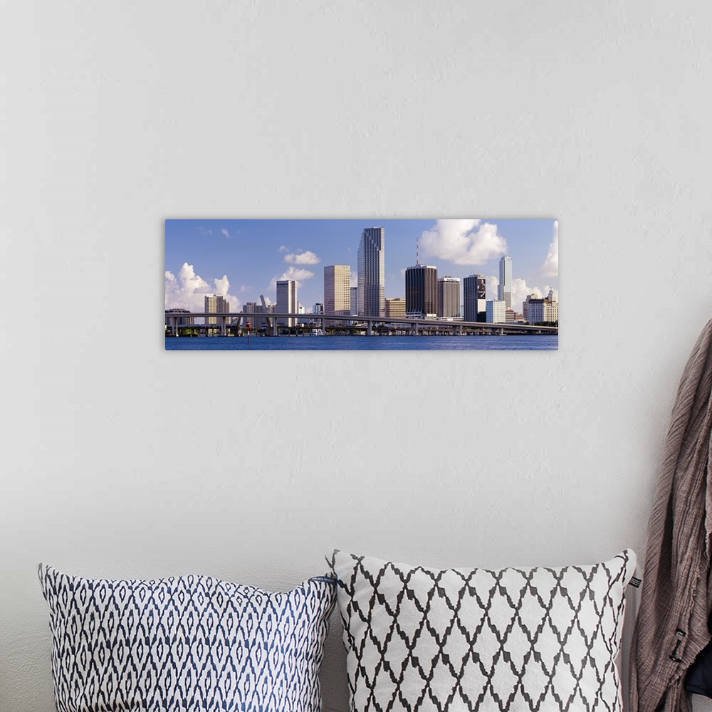 A bohemian room featuring This urban landscape wall art is the city skyline taken from the water with a roadway passing in ...