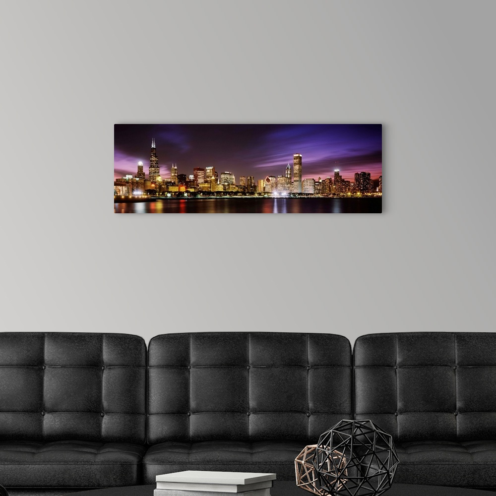 A modern room featuring A big cityscape panoramic of downtown Chicagoos lights reflecting off Lake Michigan at night.