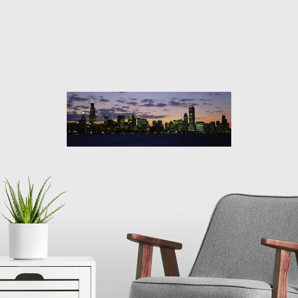 A modern room featuring Panoramic photograph shows a skyline on the edge of a river within a lively Midwestern city lit u...