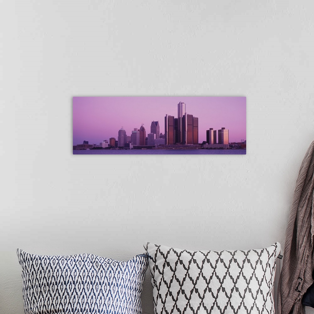 A bohemian room featuring The Detroit skyline is photographed in panoramic view from across the waterfront during dusk.