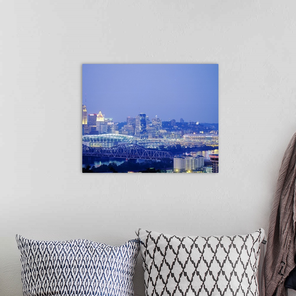 A bohemian room featuring A photograph of a bridge, stadium, and the cityos downtown illuminated at night.