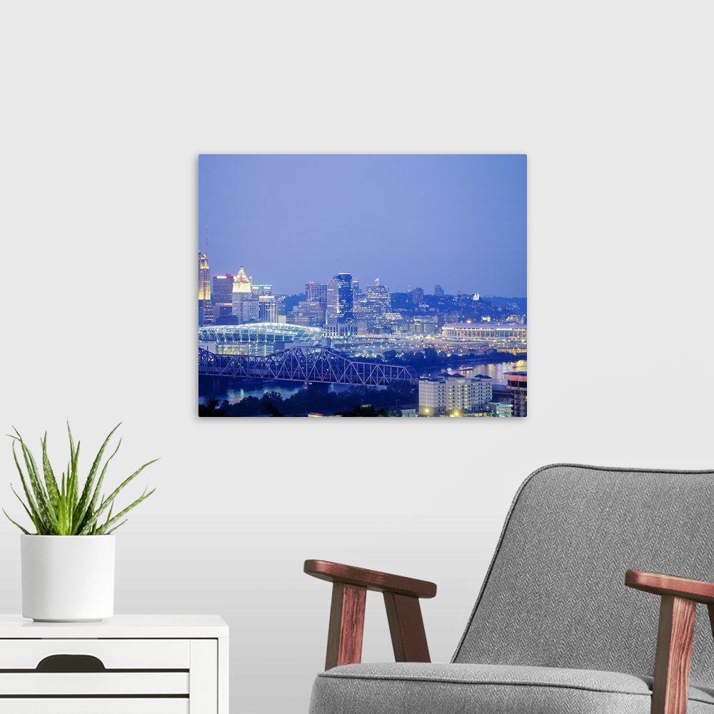 A modern room featuring A photograph of a bridge, stadium, and the cityos downtown illuminated at night.