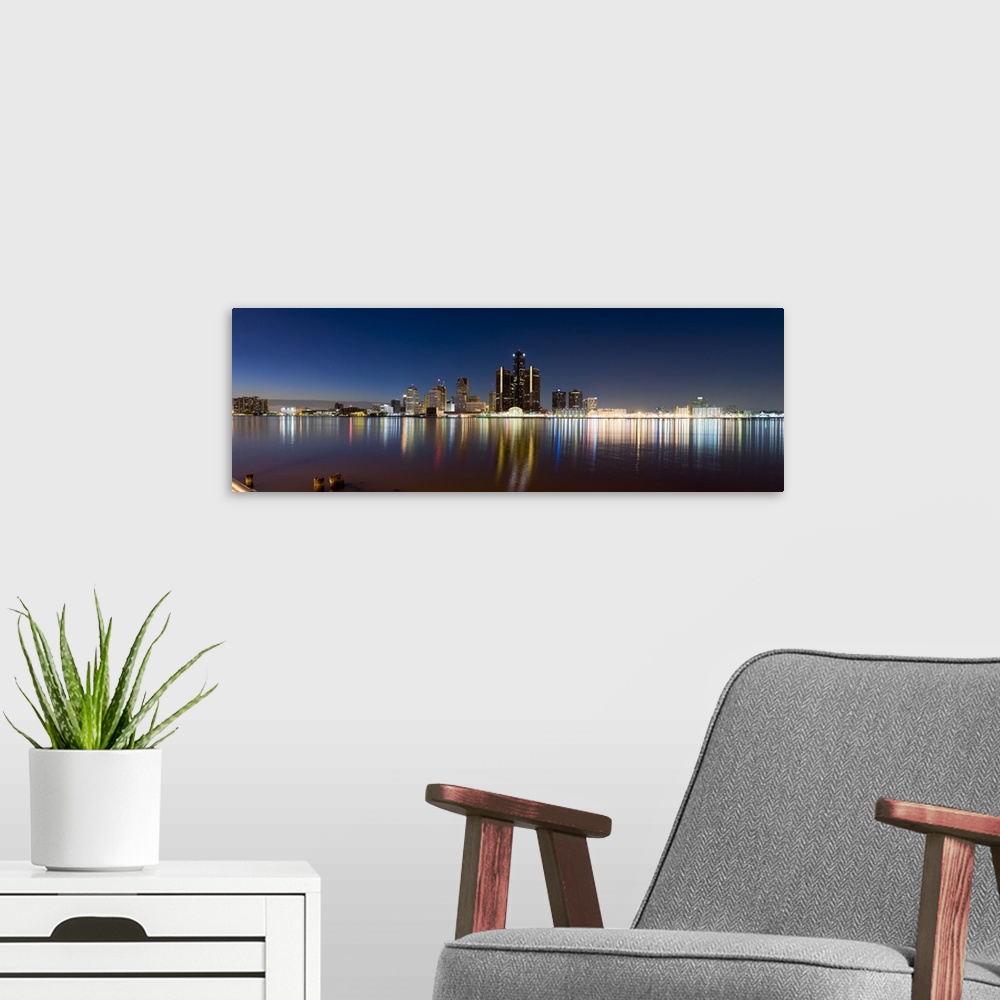 A modern room featuring Panoramic photograph of skyline and waterfront at night.  The building lights create colorful ref...