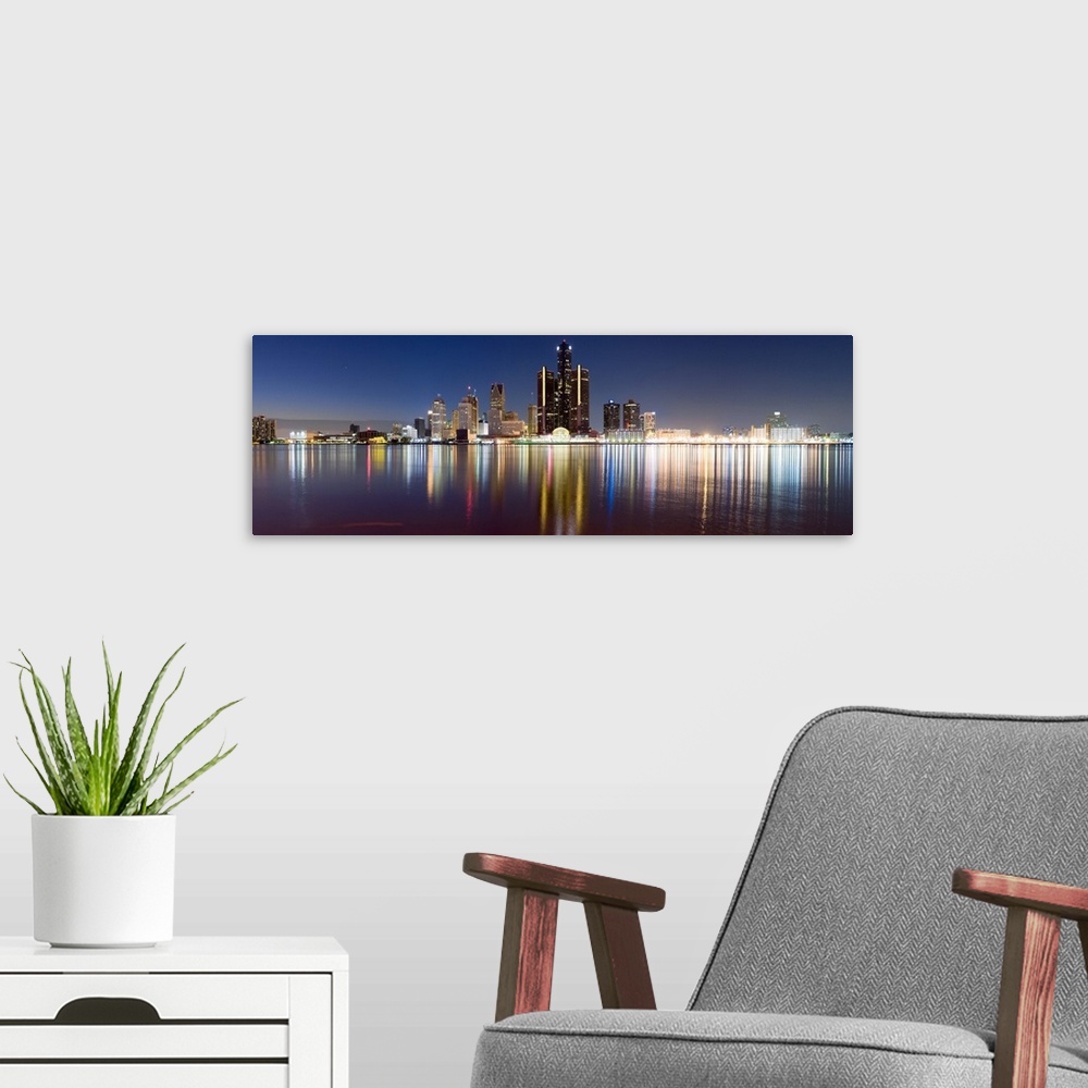 A modern room featuring Wide angle photograph of the distant Detroit skyline, lit at night and reflecting in the waters o...