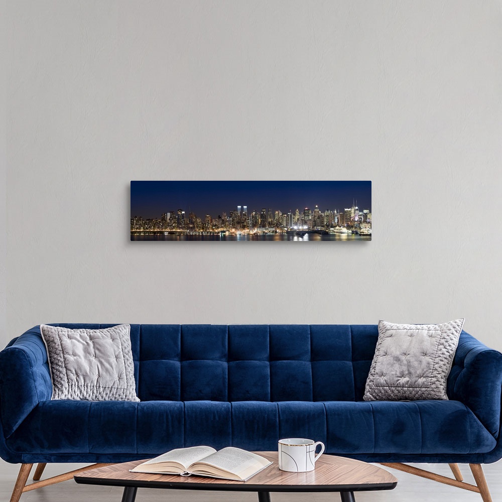 A modern room featuring This wall art is a panoramic photograph of the marvelous city skyline illuminated at night.