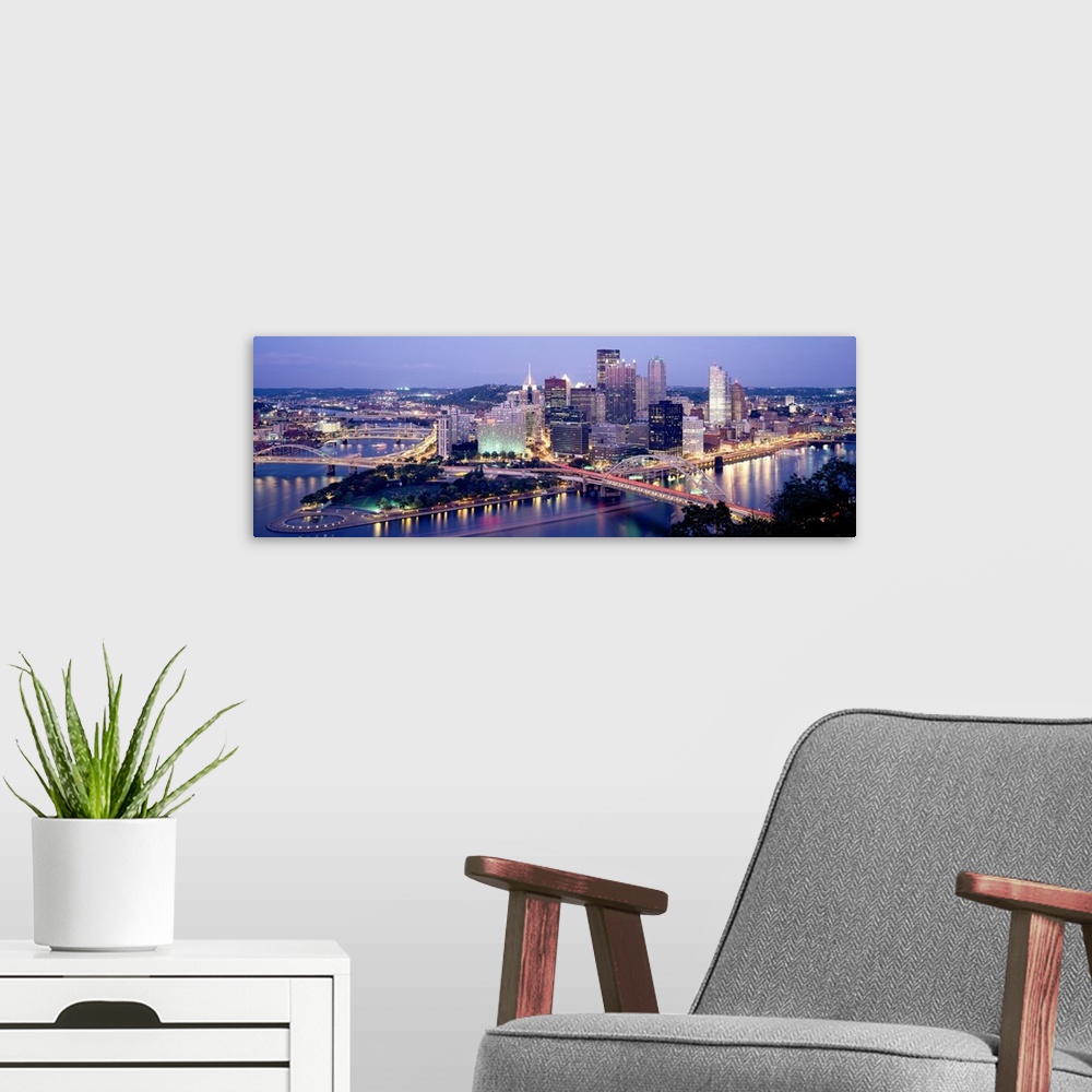 A modern room featuring Panoramic canvas of a cityscape by a river with bridges spanning across it at dusk.