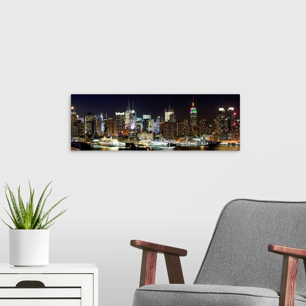 A modern room featuring Oversized panoramic photograph of brightly lit skyscrapers in Manhattan, behind the reflecting wa...