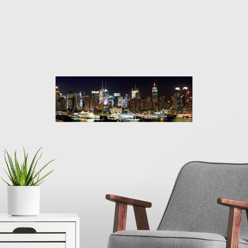 A modern room featuring Oversized panoramic photograph of brightly lit skyscrapers in Manhattan, behind the reflecting wa...